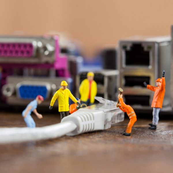 Conceptual image of miniature engineer and worker plug-in lan cable to computer